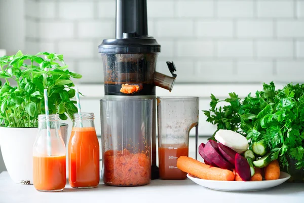 Vrouw maken vers drankje. Sapcentrifuge en wortel sap. Fruit in de achtergrond. Schoon eten, detox concept — Stockfoto