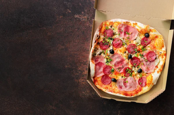 Fresh pizza in delivery box on dark concrete background. Top view, copy space