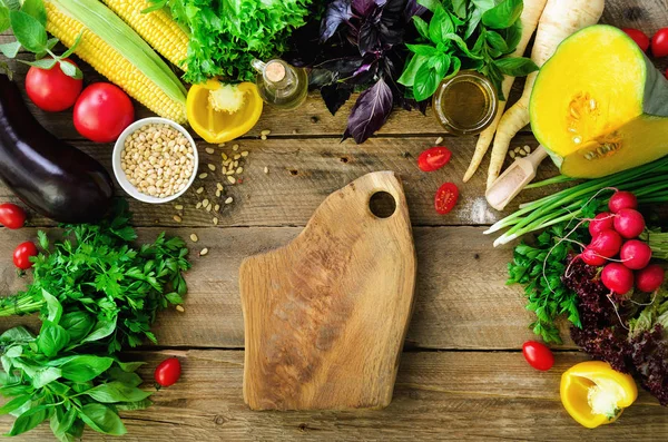 Vegetables on wooden background. Herbs, basil, onion, pumpkin, pine nuts, tomatoes, corn, radish, eggplant, bell pepper, salt, spices, oil, spinach, parsley, lettuce leaves. Top view, copy space — Stock Photo, Image