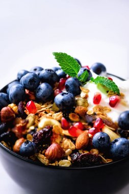 Lezzetli ev yapımı granola, yoğurt, taze organik çilek, nar, kopya alanı, üstten görünüm gri beton zemin üzerine nane.