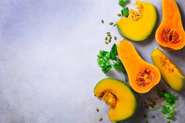 Olgun turuncu kabak tohumu ve otlar ile ışık gri arka plan üzerinde kesti. Vejetaryen ve ham organik sağlıklı gıda kavramı, diyet. Üstten Görünüm, kopya alanı