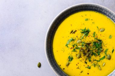 Parlak organik kabak, mercimek ve havuç çorbası tohumlar ve bitkiler üzerinde açık gri renkli. Kopya alanı, üstten görünüm