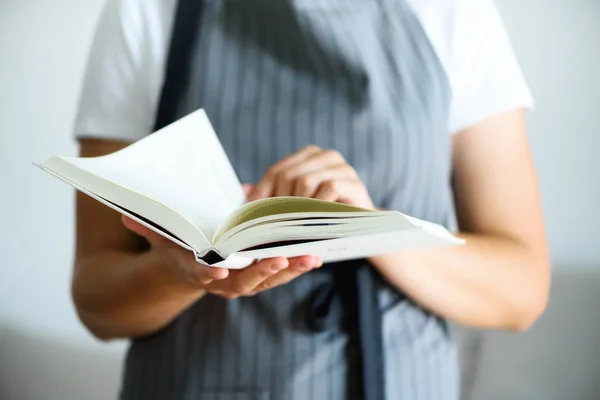 Menina vestindo avental cinza e livro de leitura. Conceito de estilo de vida — Fotografia de Stock