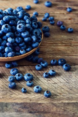 Ahşap masa üzerinde yaban mersini. Yaban mersini kase boşaltmak vintage zemin üzerine. Çilek çerçeve, sağlıklı gıda kavramı