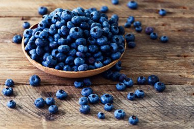 Ahşap masa üzerinde yaban mersini. Yaban mersini kase boşaltmak vintage zemin üzerine. Çilek çerçeve, sağlıklı gıda kavramı