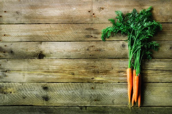 Manojo de zanahorias orgánicas frescas sobre un fondo de madera con luz solar. Concepto de dieta, comida cruda, vegetariana — Foto de Stock