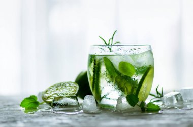 Homemade lime lemonade with cucumber, rosemary and ice, white background. Cold beverage for hot summer day. Copyspace clipart