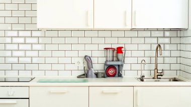 Beyaz minimalist mutfak iç ve tasarım. Döşeme duvar arka planı. Ev aletleri - blender, vakum makinesi, modern fırın, bulaşık makinesi, fırın, tablo, musluk Mikser