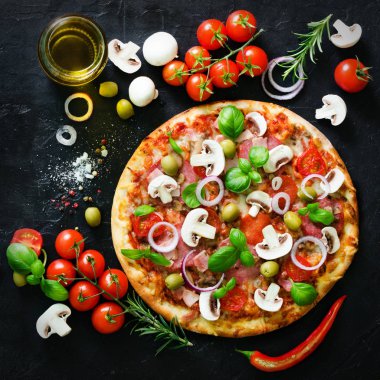 Gıda katkı maddeleri ve mantar, domates, peynir, soğan, yağ, karabiber, tuz, fesleğen, zeytin ve siyah beton zemin üzerine lezzetli İtalyan pizza yemek pişirmek için baharat. Boşaltmak. Üstten Görünüm.