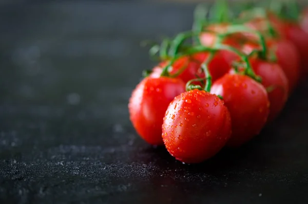 Tomates de cereja frescos em fundo preto com manjericão, temperos. Espaço de cópia . — Fotografia de Stock