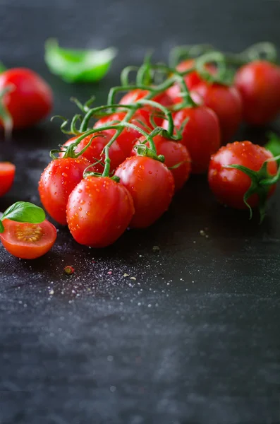 Tomates de cereja frescos em fundo preto com manjericão, temperos. Espaço de cópia . — Fotografia de Stock