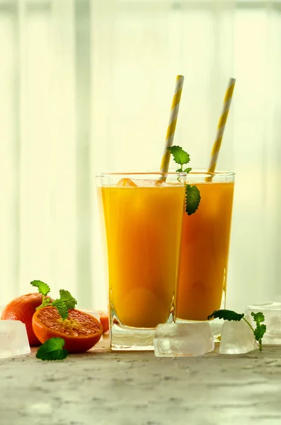 Sumo de laranja fresco, hortelã e gelo sobre fundo branco, vista superior, espaço de cópia. Cocktail de verão, bebida. Efeito tonificado . — Fotografia de Stock