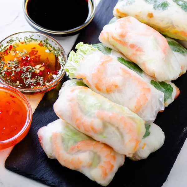 Vietnamese spring rolls - rice paper, lettuce, salad, vermicelli, noodles, shrimps, fish sauce, sweet chili, soy, lemon, veletables. Copy space. Asian and thai food. Traditional national cuisine.