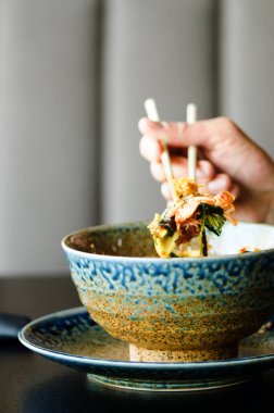 Yemek çubukları Japon, Tay dili, Çince yemek - pirinç, mantar, sebze bir plaka üzerinde tutan el mans. Kafe, Restoran. İş yemeği. Kopya alanı.