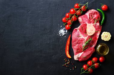 Çiğ et biftek domates, acı biber, sarımsak, yağ ve otlar karanlık taş, beton arka plan ile. Metniniz için boş alan.