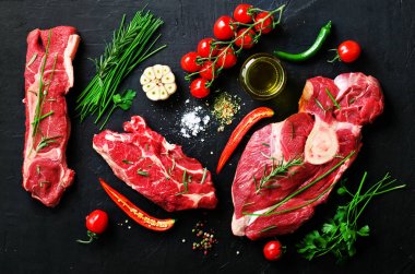 Çiğ et biftek domates, acı biber, sarımsak, yağ ve otlar karanlık taş, beton arka plan ile. Metniniz için boş alan.