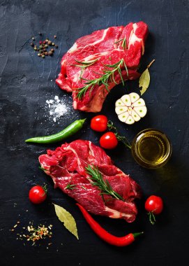 Çiğ taze et biftek domates, acı biber, sarımsak, yağ ve otlar karanlık taş, beton arka plan ile. Metniniz için boş alan