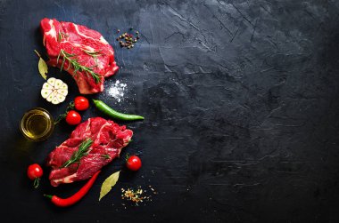 Çiğ taze et biftek domates, acı biber, sarımsak, yağ ve otlar karanlık taş, beton arka plan ile. Metniniz için boş alan