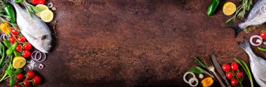 Dorada, taze balık sebze, limon, otlar, soğan, kırmızı biber, kiraz domates, soğan, salton koyu antika arka plan ile. Uzay kopyalayın. Afiş