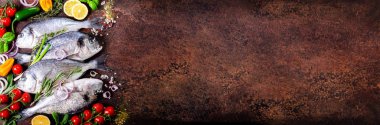 Taze çiğ balık, dorado, çipura limon, otlar, sebzeler ve baharat rustik arka plan üzerinde. Üstten Görünüm. Afiş