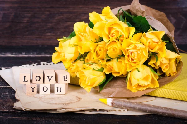 Πλαίσιο με κίτρινα τριαντάφυλλα, εκλεκτής ποιότητας χαρτί, σημειωματάριο και μολύβι στο παλιό ξύλινο υπόβαθρο. Ελεύθερο χώρο για το κείμενό σας — Φωτογραφία Αρχείου