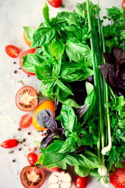 Taze ıspanak, yeşil soğan, fesleğen, otlar, dereotu ve seçici odak gri beton zemin üzerine domates. Üstten Görünüm. Tonda etkisi. Malzemeler Food yemek. Vegan, ham, detoks kavramı
