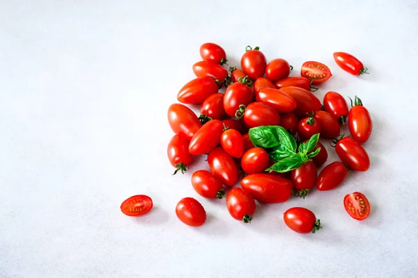 Tomate cereja em fundo cinza com copyspace. Tomates vermelhos, amarelos e pretos, folhas de manjericão . — Fotografia de Stock