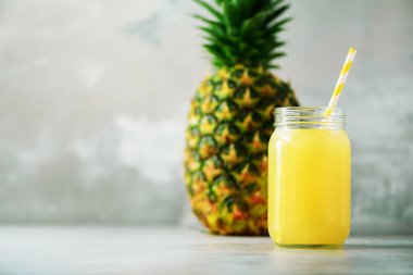 Cam Kavanoz ananas güler yüzlü ve gri arka plan üzerinde meyve. Uzay kopyalayın. Yaz, tatil kavramı. RAW, vegan, vejetaryen, beslenmenin temiz.