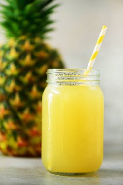 Cam Kavanoz ananas güler yüzlü ve gri arka plan üzerinde meyve. Uzay kopyalayın. Yaz, tatil kavramı. RAW, vegan, vejetaryen, beslenmenin temiz.