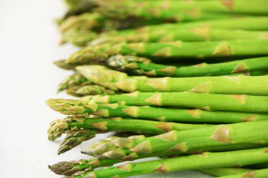 Gri zemin üzerine yeşil taze kuşkonmaz. Üstten Görünüm. RAW, vegan, vejetaryen ve temiz yemek kavramı.