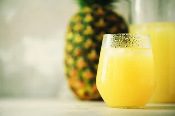 Jugo de piña en cristalería y fruta de piña entera sobre fondo gris. Copiar espacio, efecto de luz solar. Verano, concepto de vacaciones. Dieta de alimentación cruda, vegana, vegetariana y limpia . —  Fotos de Stock