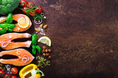 Çiğ somon fileto aromatik bitkiler, soğan, avokado, brokoli, biber bell, ahşap arka plan, üstten görünüm üzerinde sebze ile balık. Arka plan üzerinde yemek pişirmek için malzemeler.
