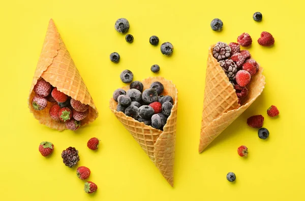 Frozen berries - strawberry, blueberry, blackberry, raspberry in waffle cones on yellow background. Top view. Banner. Pattern for minimal style. Pop art design, creative concept — Stock Photo, Image