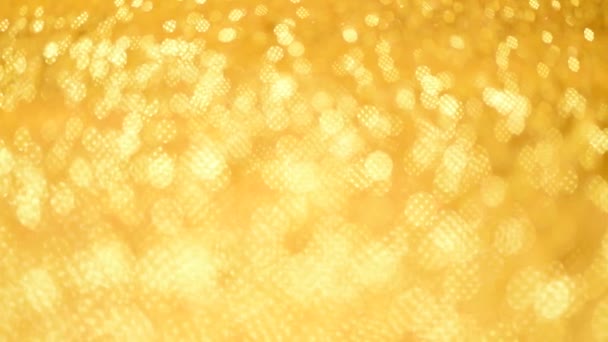 Złote, błyszczące tło świątecznych pozdrowień. Baner z rozproszonymi światłami, jasnożółty bokeh. Błyszczyk o złotej strukturze brokatu. Koncepcja Nowego Roku, luksusowe wakacje. — Wideo stockowe