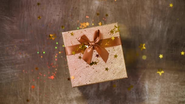 Sparkling gold stars, glitter confetti over gift box. Top view. Christmas and New year texture. Sales, discount price, shopping concept. — 비디오