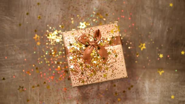 Sparkling gold stars, glitter confetti over gift box. Top view. Christmas and New year texture. Sales, discount price, shopping concept. — 비디오