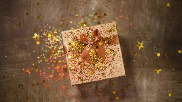 Sparkling gold stars, glitter confetti over gift box. Top view. Christmas and New year texture. Sales, discount price, shopping concept. — 비디오