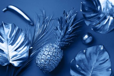 Boyalı egzotik meyveler, tropik palmiye ağaçları, klasik mavi arka planda canavar yaprakları. Üst Manzara. Düz yatıyordu. Yemek konsepti. Monokrom ananas, muz, limon ve kopya alanının yaratıcı düzeni.