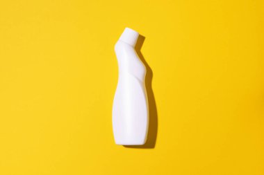 Beyaz plastik temizlik ürünü şişesi, ev kimyasalları ya da sarı arka planda sıvı çamaşır deterjanı. Üst Manzara. Düz yatıyordu. Uzayı kopyala Deterjan şişesi.