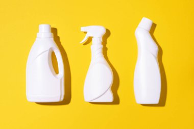 Sarı arka planda plastik temizlik ürünleri içeren kompozisyon. Üst Manzara. Düz yatıyordu. Uzayı kopyala Plastik atık. Deterjan şişesi deseni