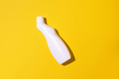 Beyaz plastik temizlik ürünü şişesi, ev kimyasalları ya da sarı arka planda sıvı çamaşır deterjanı. Üst Manzara. Düz yatıyordu. Uzayı kopyala Deterjan şişesi.