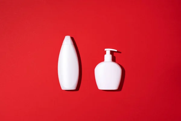 Shampoo dan botol sabun dengan latar belakang merah. Pemandangan bagus. Berbaringlah. Salin ruang. — Stok Foto