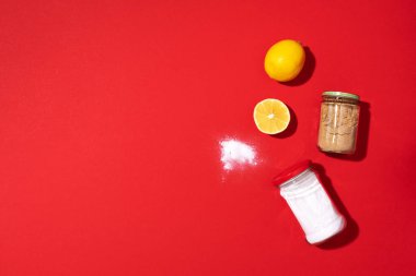 Çevre dostu doğal temizleyicilerle düz kompozisyon. Kırmızı arka planda kabartma tozu, tuz, limon ve hardal tozu. Üst Manzara. Uzayı kopyala Düz yatıyordu. Ev yapımı yeşil temizlik..