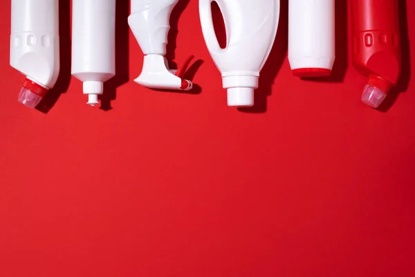 Detergent bottles and chemical cleaning supplies on red background. Top view. Copy space. Flat lay. — Stock Photo, Image