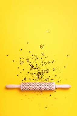 Yuvarlanan iğne, sarı arka planda altın parıltılı yıldızlar. Üst Manzara. Uzayı kopyala Noel pişirme konsepti. Tatil kompozisyonu. Menü, tarif, malzemeler için pankart