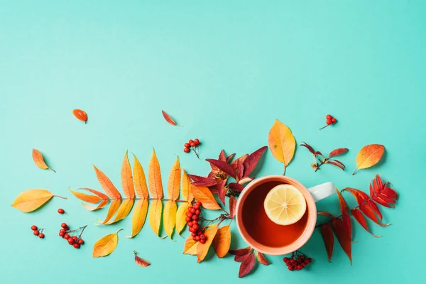 Autumn flat lay composition. Cup of tea, autumn bright leaves on blue background. Top view. Flat lay. Autumn season concept
