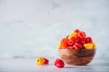 Sarı ve kırmızı viski kapşonlu kırmızı biberli ahşap kasede gri arka planda. Boşluğu kopyala.