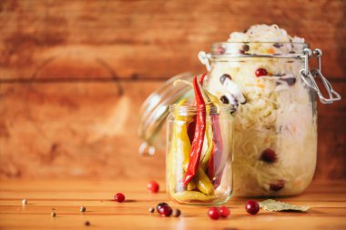 Ahşap arka planda çeşitli mayalanmış ve marine edilmiş yiyecekler, kopyalama alanı. Mayalanmış sebze, lahana turşusu, biber, sarımsak, pancar, Kore havucu, cam kavanozlarda salatalık turşusu..