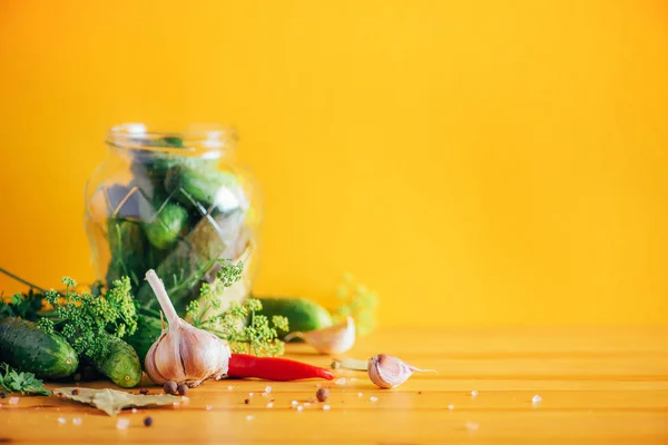 Sottaceto cetrioli in lattine. Ingredienti per cetriolini marinati, barattolo di vetro, aglio, aneto, sale, pepe su fondo giallo. Ricevuto. Concetto di conservazione delle verdure . — Foto Stock