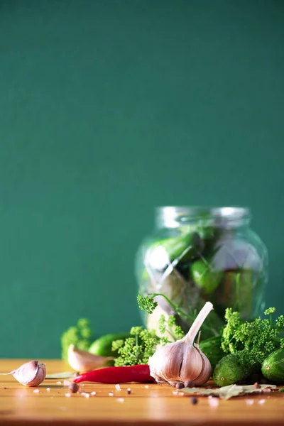 Sottaceto cetrioli in lattine. Ingredienti per cetriolini marinati, barattolo di vetro, aglio, aneto, sale, pepe su fondo verde. Ricevuto. Concetto di conservazione delle verdure . — Foto Stock